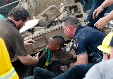 A boy is pulled from beneath a collapsed wall at the Plaza Towers Elementary School following a tornado in Moore, Okla., Monday, May 20, 2013.